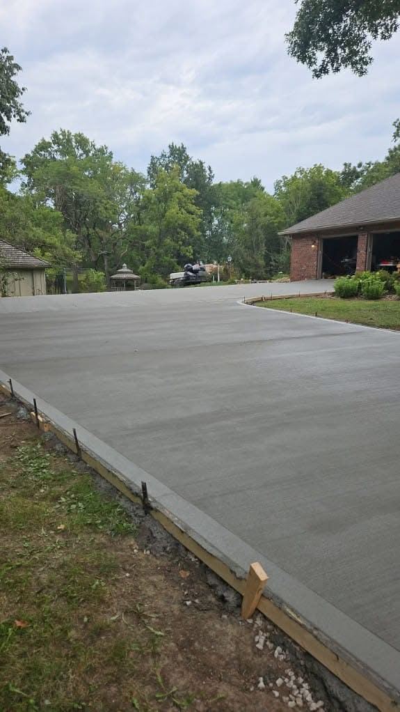 Completed broom-finish concrete driveway leading to a brick home