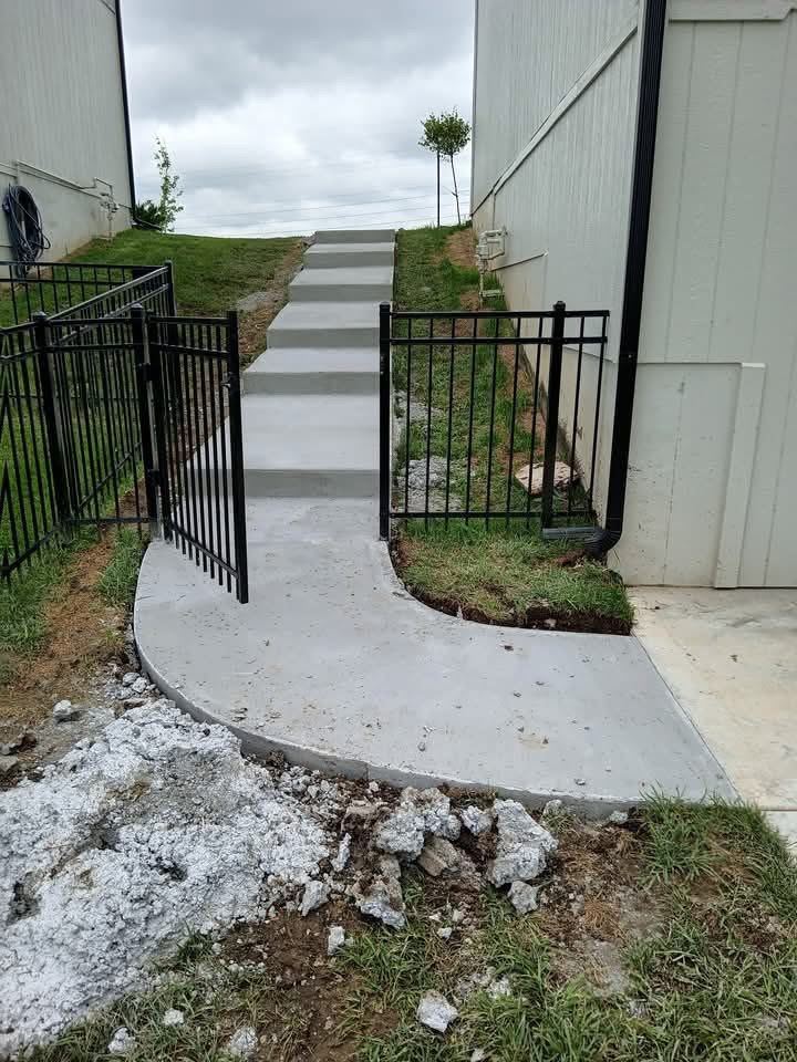 Completed concrete walkway and steps running up a slope between buildings