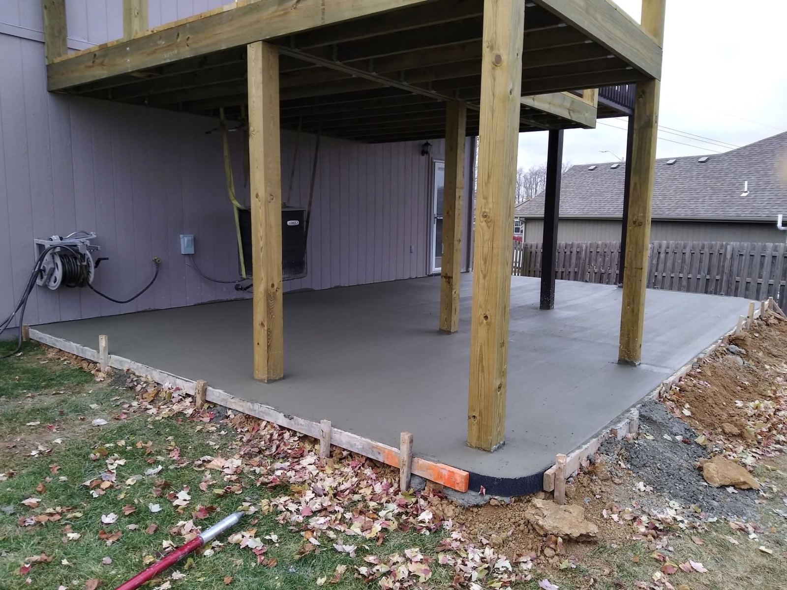 Large concrete patio slab poured beneath a wooden deck