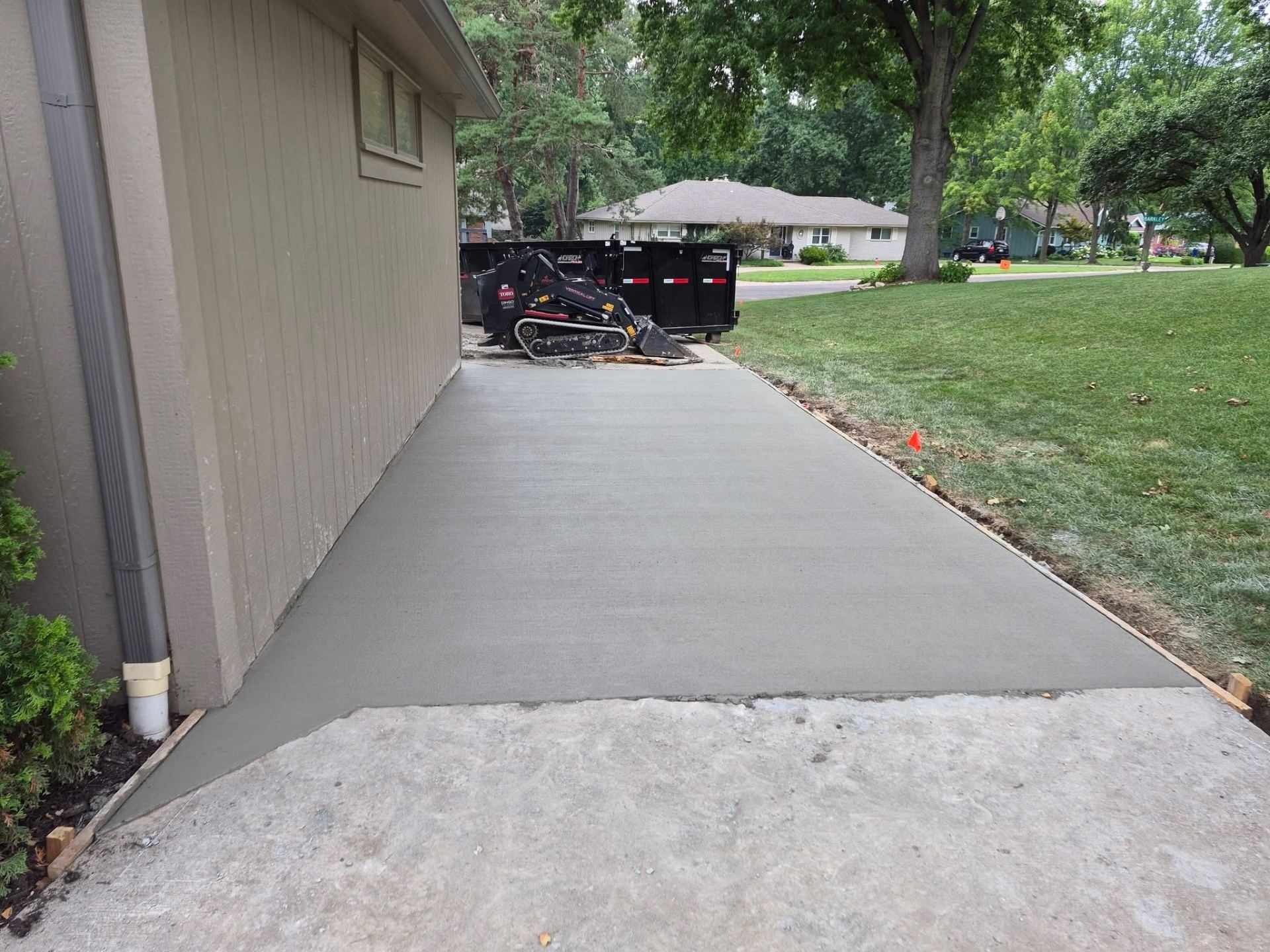 Freshly poured concrete driveway running alongside a home
